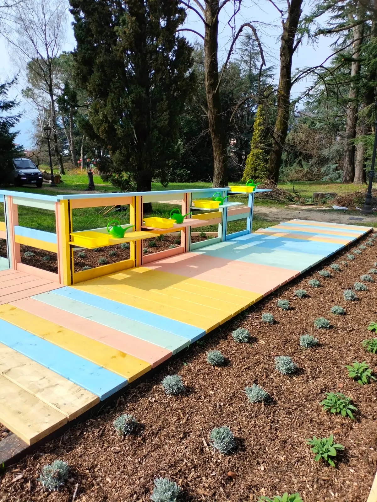 La piattaforma colorata del parco aromatico sensoriale, con fioriere ad altezza regolabile e annaffiatoi per i bambini